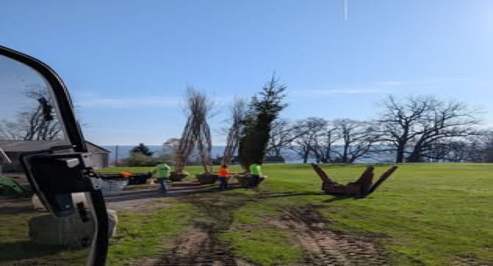 Equipment staged beside tire-marked lawn and open grass